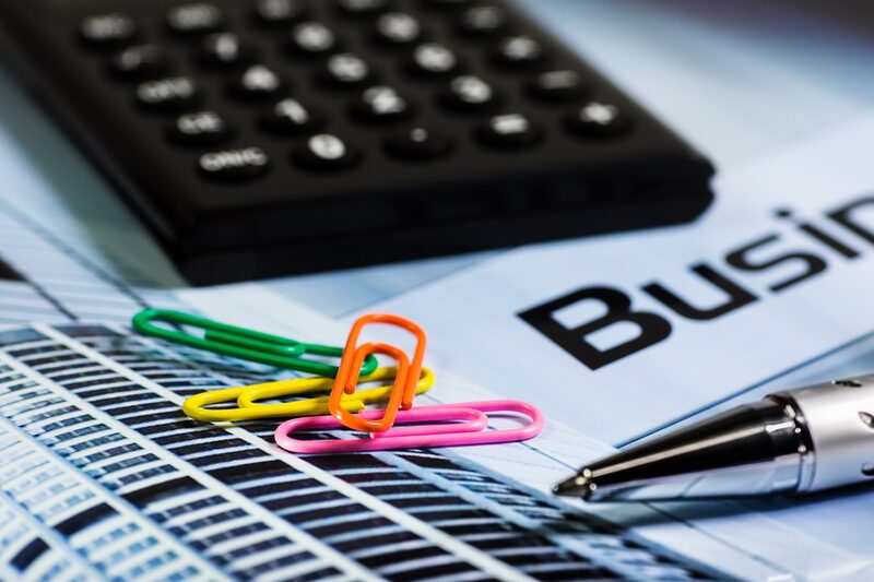 Büro-Utensilien wie Taschenrechner, Büroklammern, Stift, Notizheft