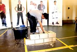 Ein Handwerker zeigt, wie man eine Mauer richtig hochzieht.