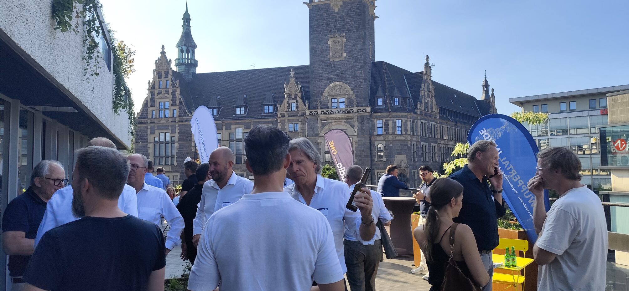 Menschen auf einer Dachterrasse, im Hintergrund das Rathaus Elberfeld